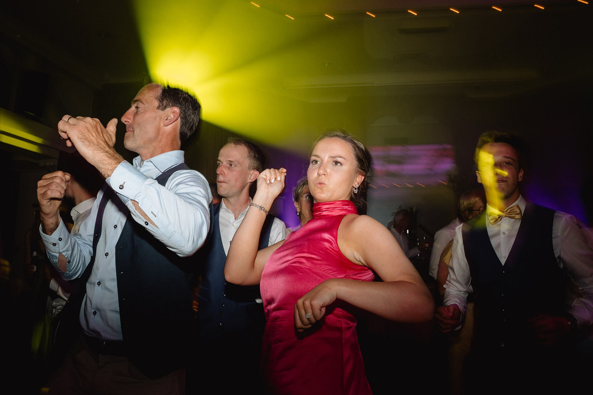 Gasten dansen in geel en paars licht